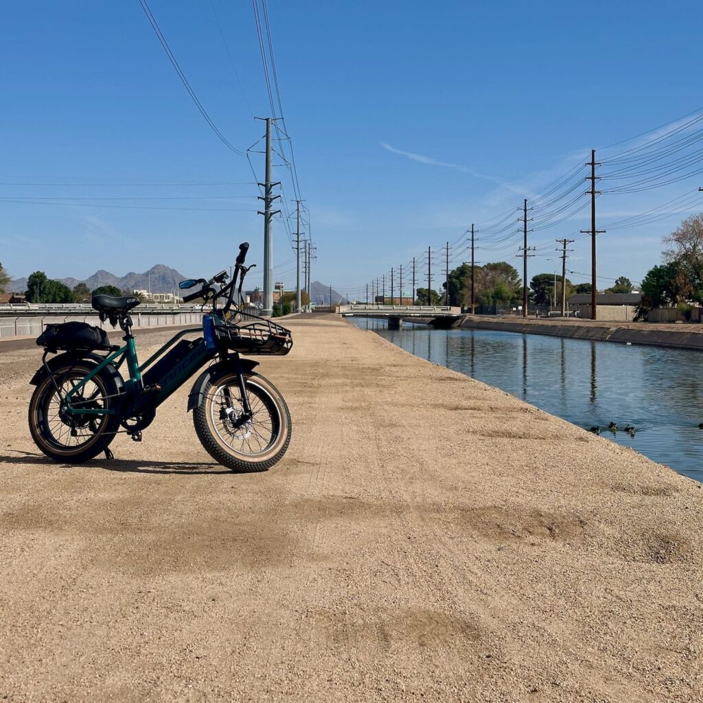 ebike parked along side a canal. There are ducks in the canal and the power lines line up nicely.